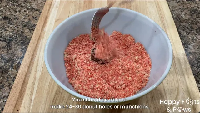 Using a fork to cover the dipped donut in butternut streusel crumb toppings