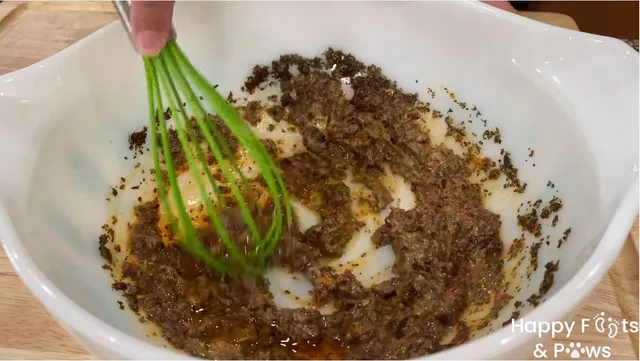 wisking sun dried tomato vinaigrette in a glass bowl