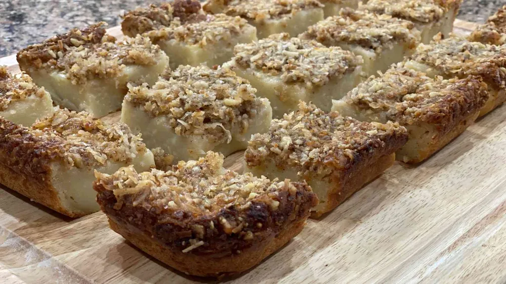 Hawaiian Butter Mochi cut into squares on a wooden cutting board