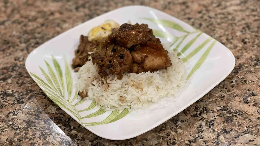 A plate with chicken, jasmin rice, eggs, and, pork filipino adobo