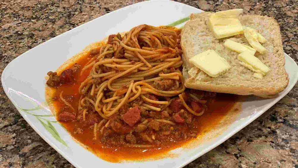 sweet filipino spaghetti with french bread, hotdog, and sausage.