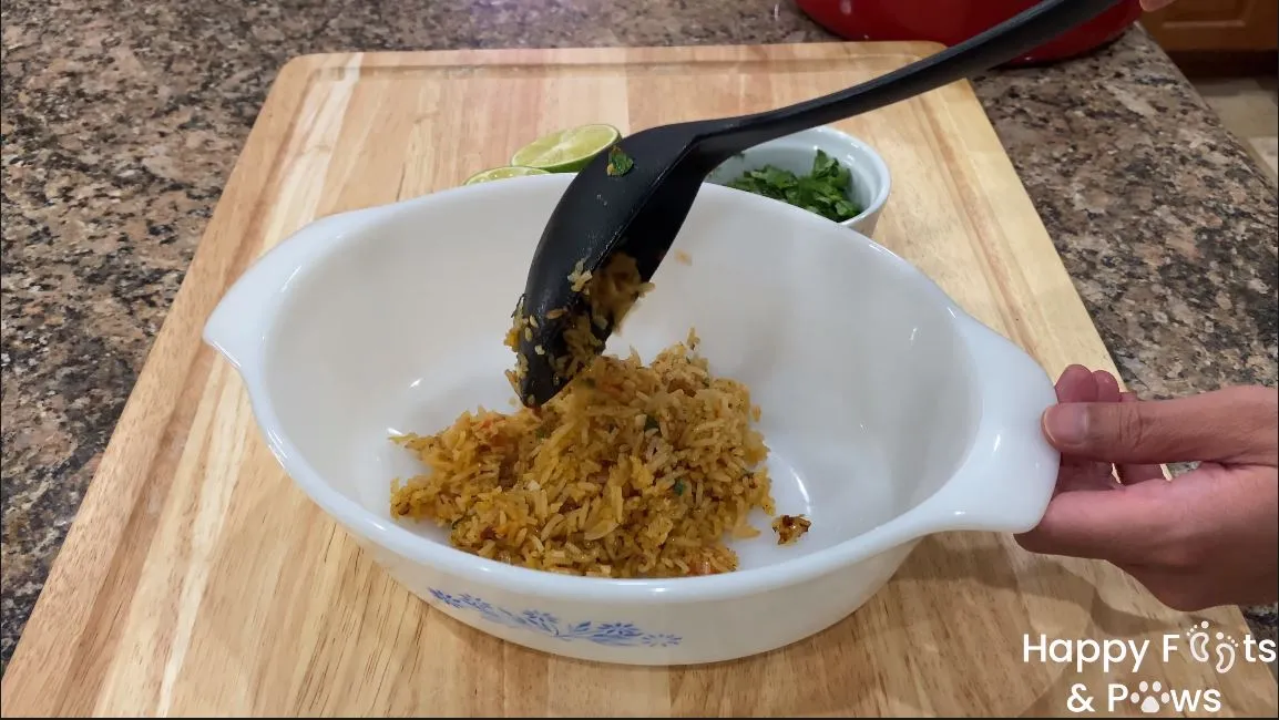 a scoop of spanish rice being added to a glass bowl