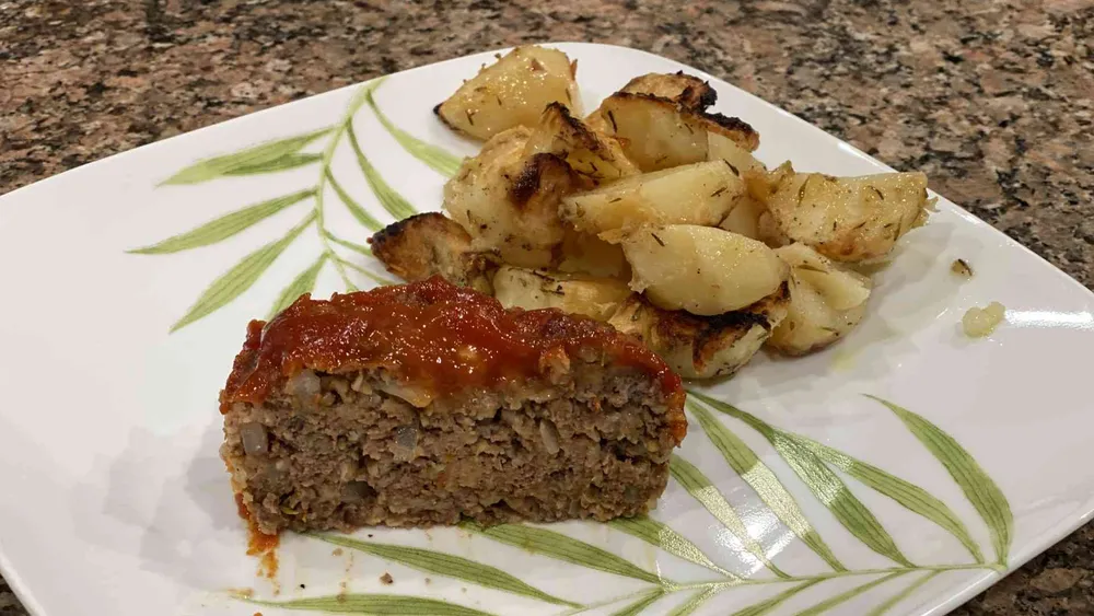 homemade meatloaf on plate with oven baked potatos