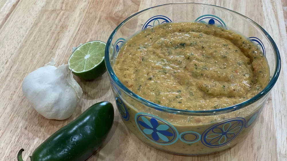 mango salsa in a bowl with jalapeno, lime, and garlic next to bowl