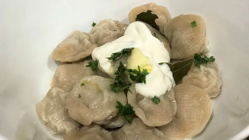 Homemade cooked pelmeni with sour cream in a bowl