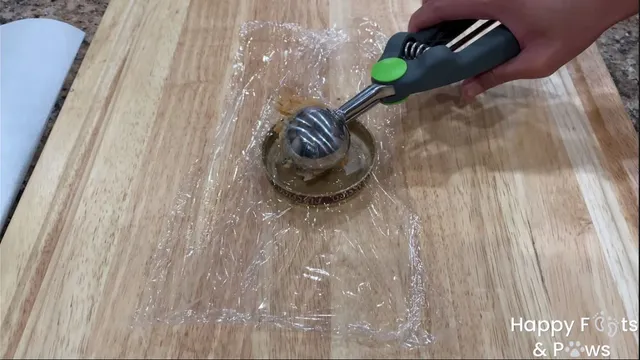 Hand with ice cream scoop placing raw shrimp cake into lid