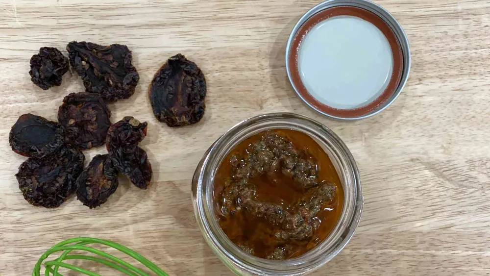 Sun-Dried Tomato Vinaigrette in glass container next to sundried tomatoes